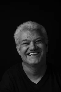 Schwarz weiss Foto eines grauhaarigen Mannes der herzlich lacht